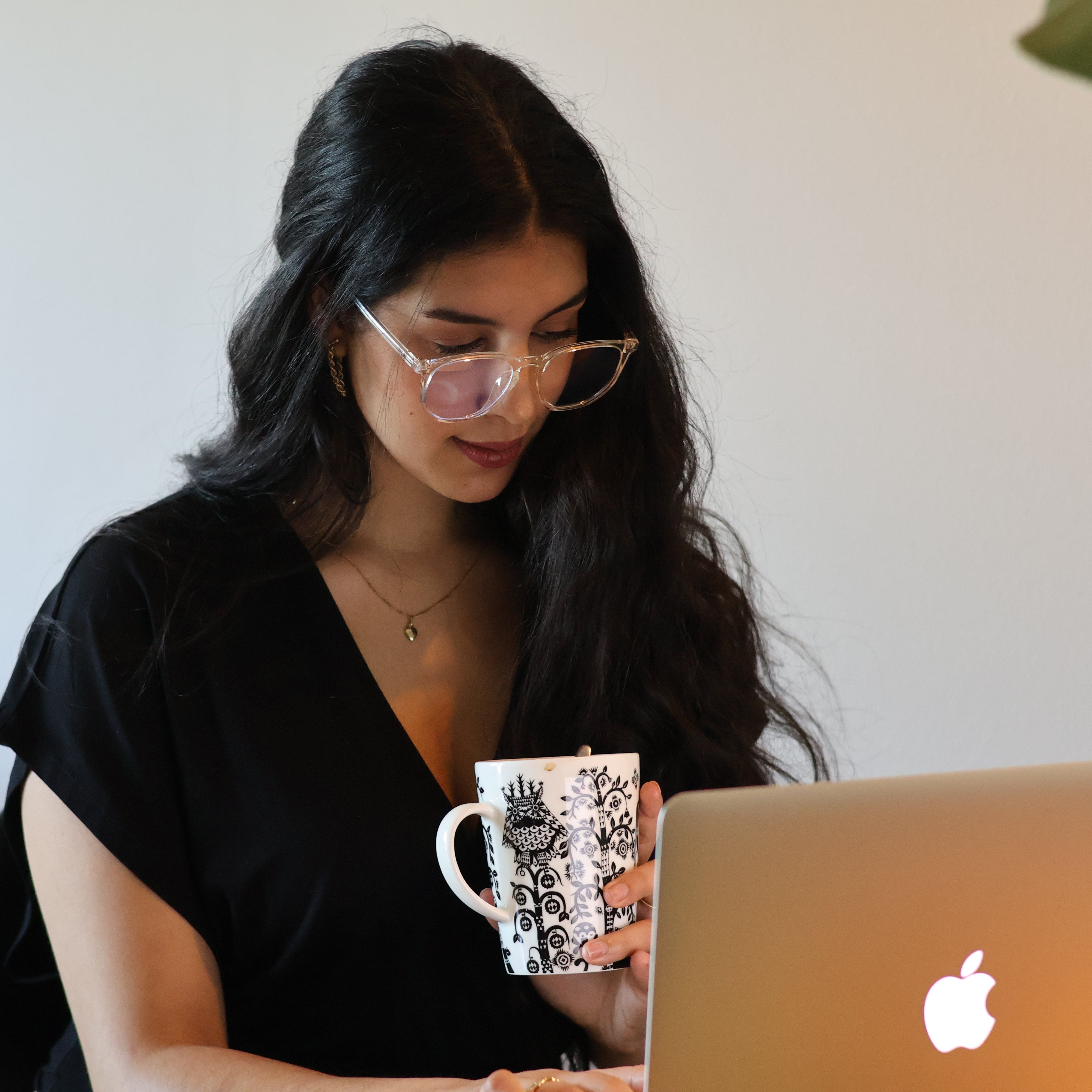 Nainen NordicRest sinivalolaseilla työskentelemässä kannettavalla tietokoneella kahvikuppi kädessä